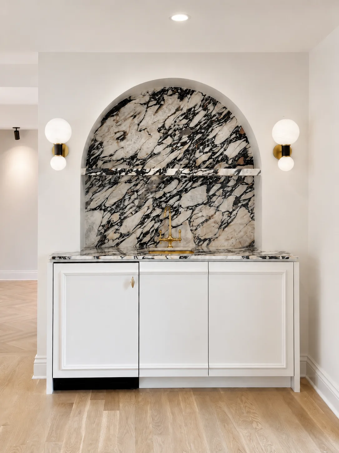 White bar cabinetry and trim surrounding an arched black-and-white stone niche