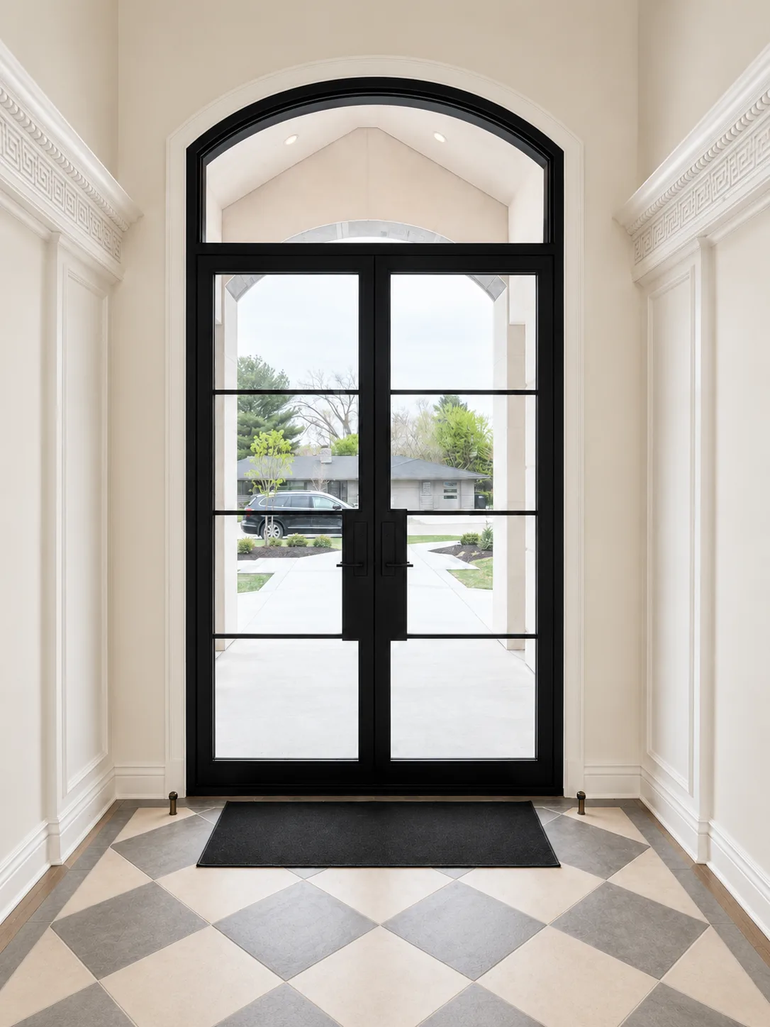 Tall black arched entry door framed by finished white walls and classical entry millwork