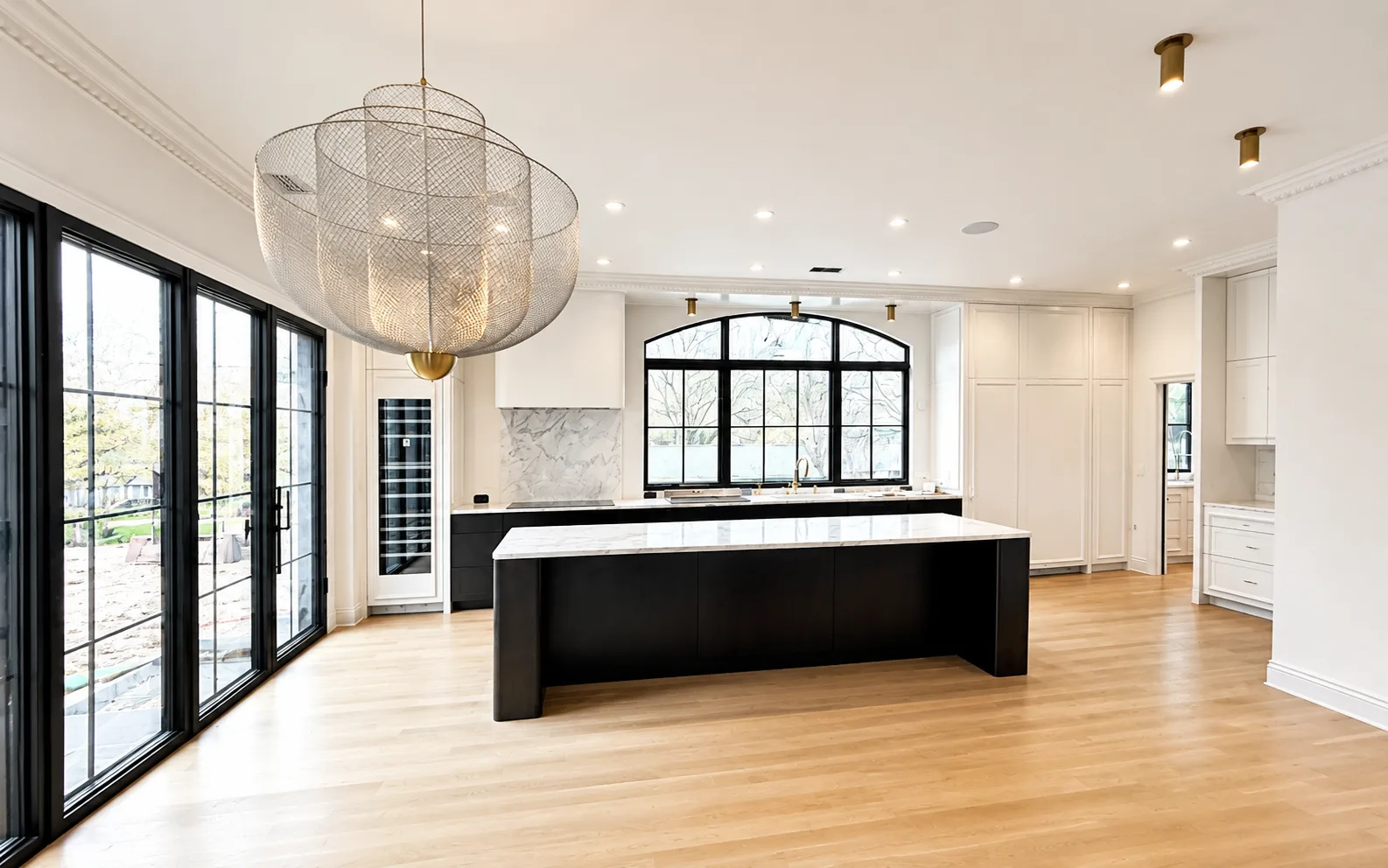 Completed black-and-white kitchen with painted cabinetry, a dark island, and crisp architectural trim