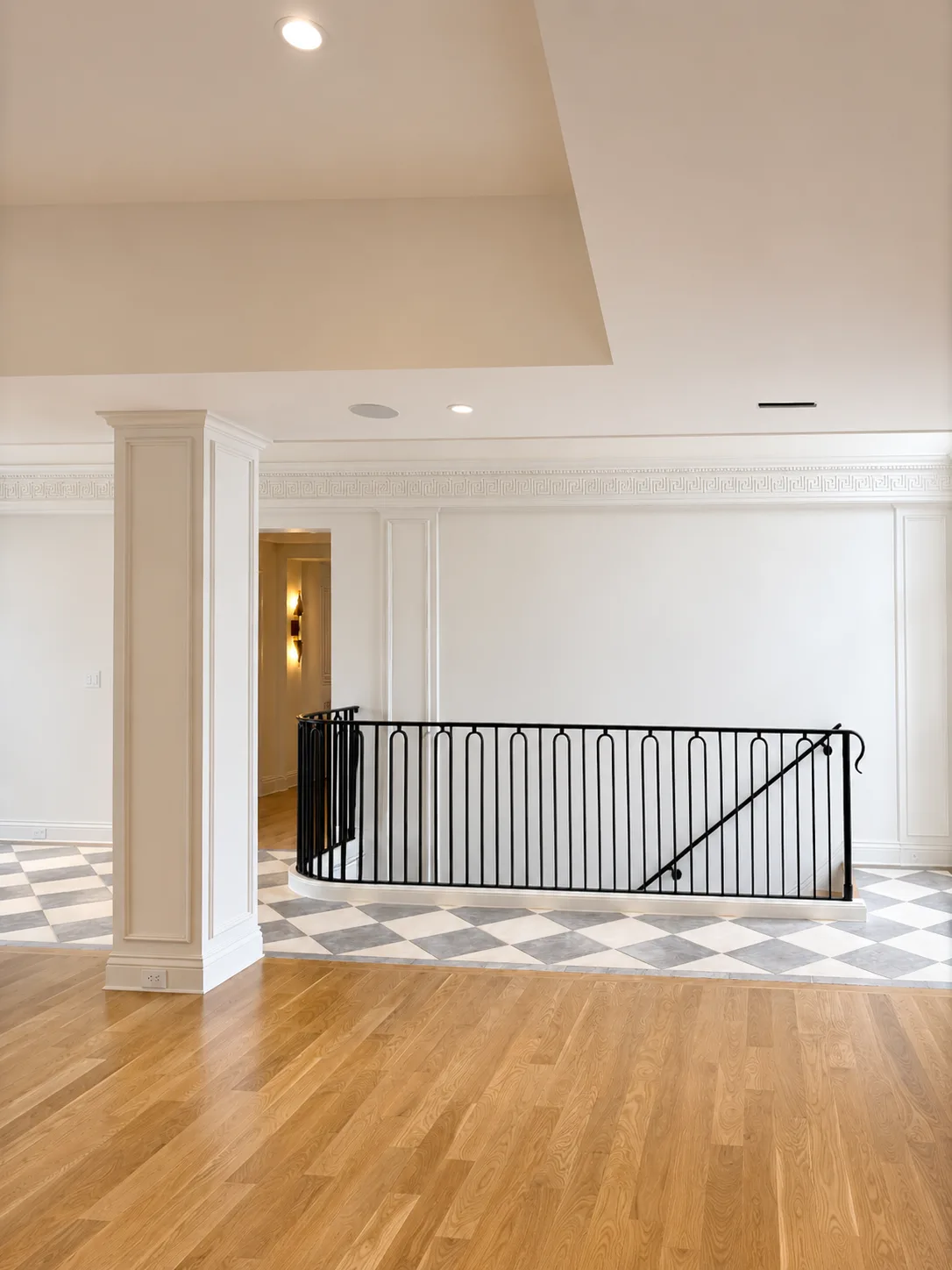 Finished stair landing with white accent millwork, black railings, and checkerboard flooring