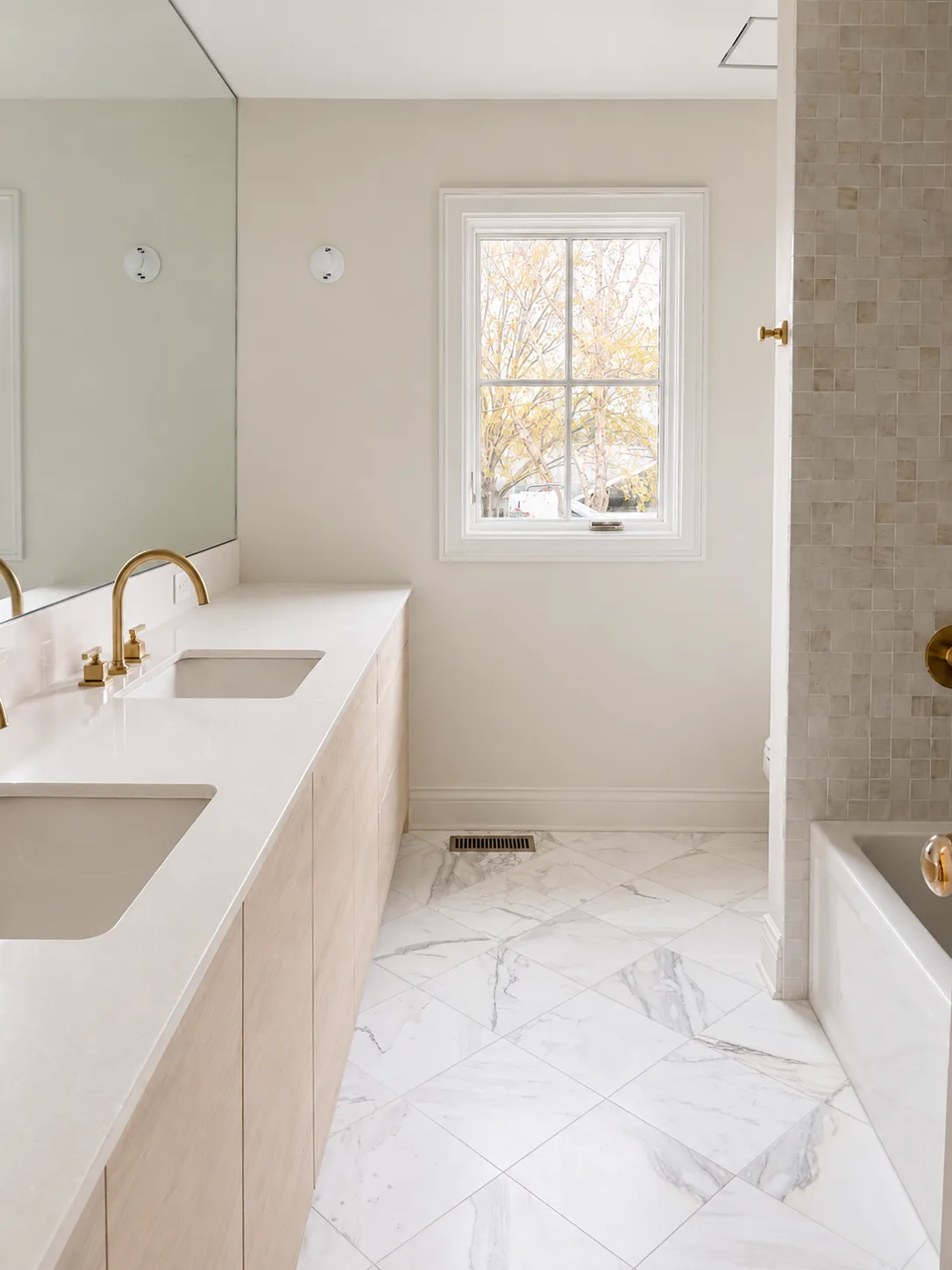 Light bathroom with soft neutral walls, white trim, marble flooring, and brass fixtures