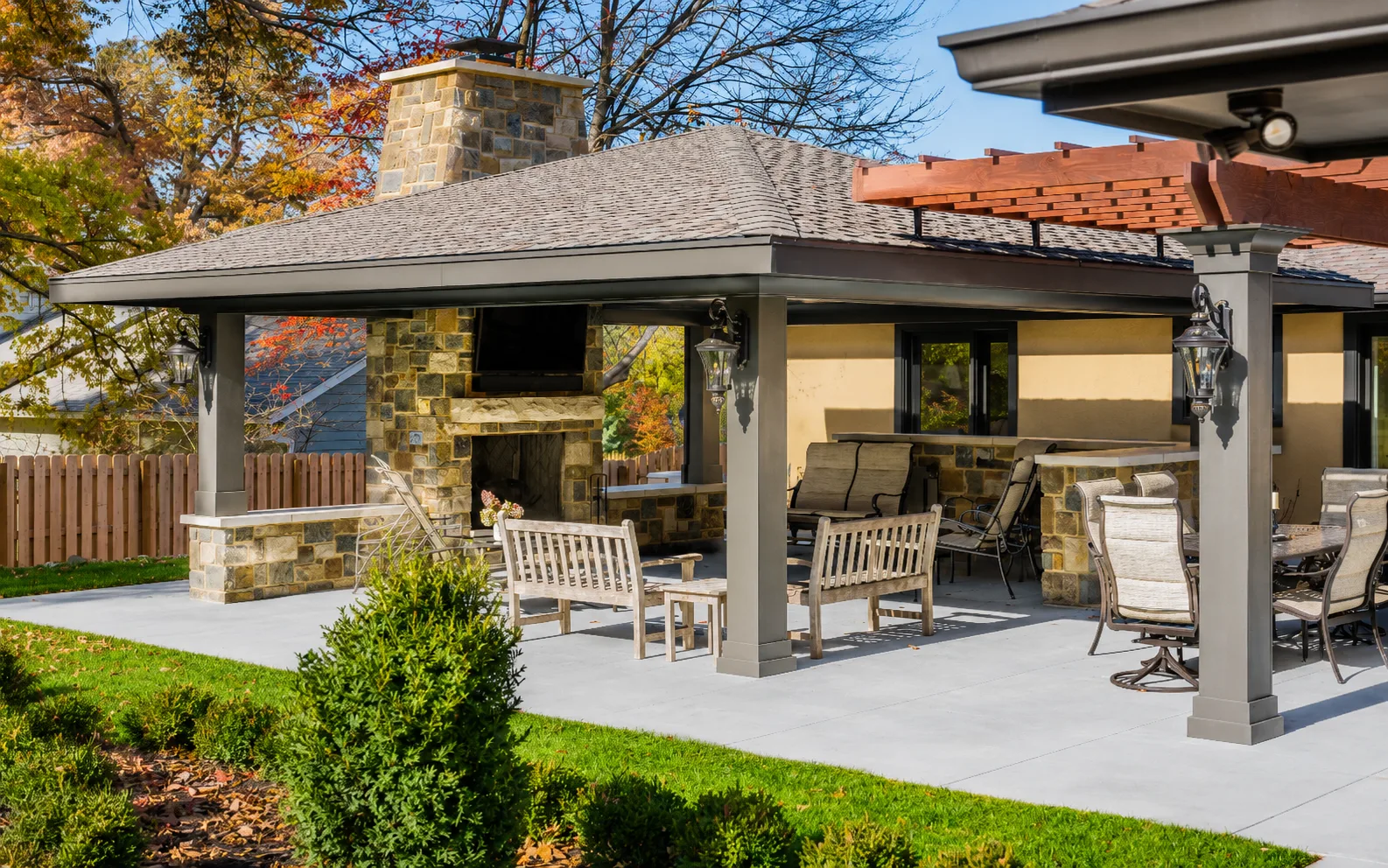 Completed covered outdoor pavilion with painted posts and trim, stained wood, and a stone fireplace