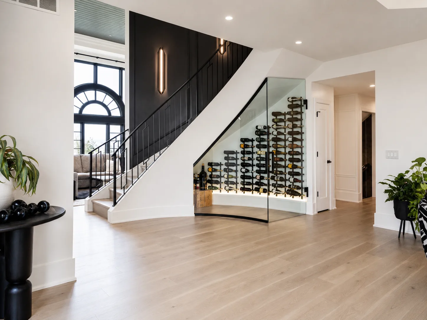 Finished stair hall with a dark paneled wall, white walls and trim, and a glass wine display