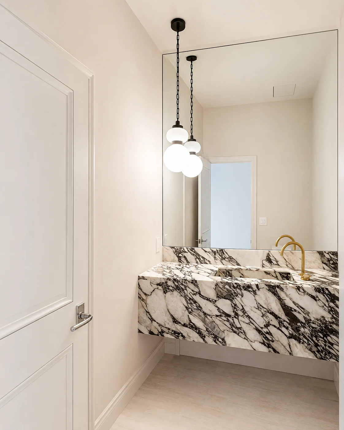Bright powder room with crisp white walls and trim, a dramatic stone sink, and brass fixtures
