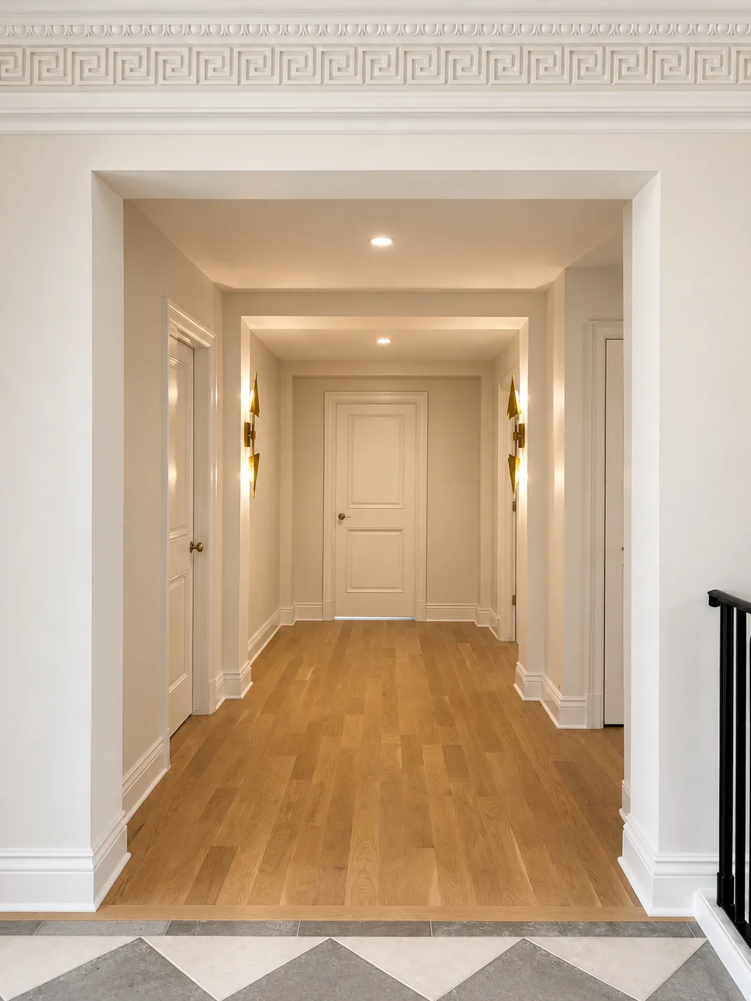 Finished warm neutral hallway framed by white doors, trim, and detailed classical molding